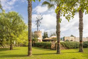 un molino de viento en un parque con palmeras en Hotel Rural Xereca en Puig D’en Valls