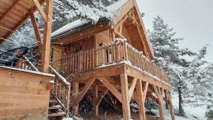 a wooden cabin with snow on the deck at Chalet l'Empreinte in Saint-Étienne-de-Tinée
