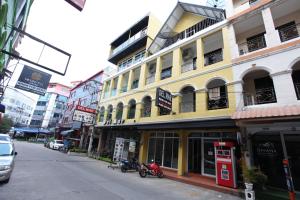a yellow building on a city street with cars at Del Mar Rooms in Pattaya South