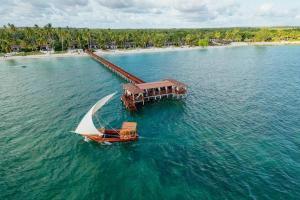 a boat in the water next to a beach at The Residence Zanzibar in Kizimkazi