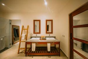 Kivuli Beach Resort Paje في باجي: حمام به مغسلتين ومرايا على الحائط
