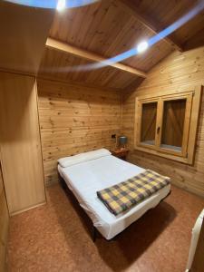 ein Schlafzimmer mit einem Bett in einer Holzhütte in der Unterkunft Bungalow & Camping Fuente De Regrustan in Graus