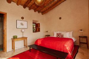 1 dormitorio con cama roja y banco en Dar Imiri, en Ourika