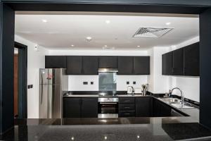 une cuisine avec armoires noires et appareils en acier inoxydable dans l'établissement WSuites - Big Terrace with Beautiful Marina View, à Dubaï