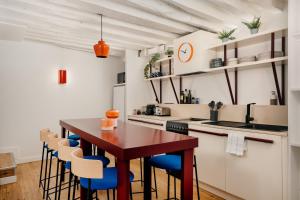 a kitchen with a wooden table and blue chairs at Edgar Suites Marais - Nazareth in Paris