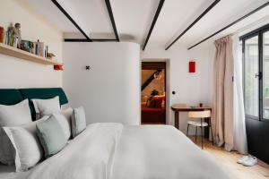 a bedroom with a large white bed and a table at Edgar Suites Marais - Nazareth in Paris