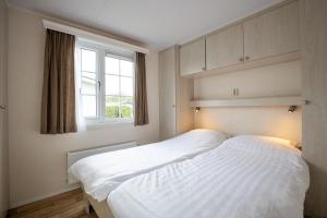 een slaapkamer met 2 witte bedden en een raam bij Strandcamping Valkenisse in Biggekerke