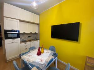 uma cozinha com uma mesa e uma televisão numa parede amarela em Sendy Home Roccaraso 3 em Roccaraso