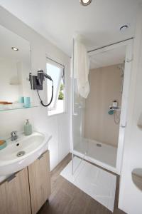 a white bathroom with a sink and a shower at Camping les Cantarelles in Alrance