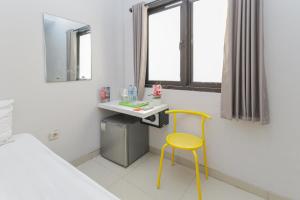 泗水的住宿－RedDoorz Plus At K23 Rungkut Madya，一间设有黄色椅子和一张书桌的房间