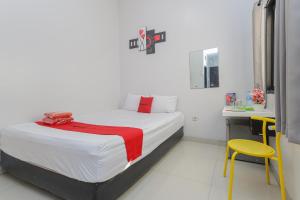 a bedroom with a bed and a yellow chair at RedDoorz Plus At K23 Rungkut Madya in Surabaya