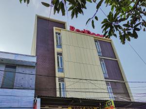 RedDoorz Plus At K23 Rungkut Madya في سورابايا: مبنى طويل مع لهجات حمراء فوقه