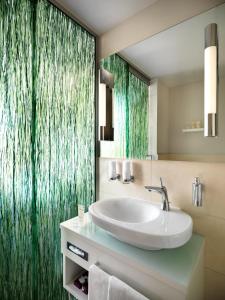 a bathroom with a sink and a green shower curtain at Giardino Lago in Locarno