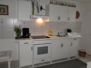 a kitchen with white cabinets and a sink at Ferienwohnung Hotte´s Hütte in Ettenheim