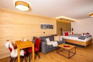 ein Wohnzimmer mit einem Sofa und einem Bett in der Unterkunft Ferienwohnungen & Chalets Capricorno in Mittelberg