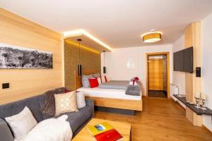 pokój hotelowy z łóżkiem i kanapą w obiekcie Ferienwohnungen & Chalets Capricorno w mieście Mittelberg