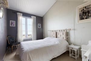 1 dormitorio con cama blanca y ventana en Appartement Neptune, en Saint-Martin-de-Ré
