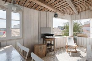 a screened in porch with a stove and chairs at Appartement Neptune in Saint-Martin-de-Ré