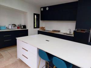 eine Küche mit einer weißen Theke und blauen Stühlen in der Unterkunft Maison de 4 chambres avec jardin clos a Saint Cast le Guildo a 1 km de la plage in Saint-Cast-le-Guildo