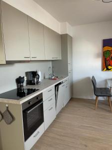 a kitchen with white cabinets and a stove top oven at H&H Apartment im Herzen von Greifswald Zentral in der Langen Reihe in Greifswald