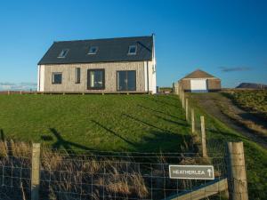 a house on top of a green hill with a fence at Heatherlea in Carinish