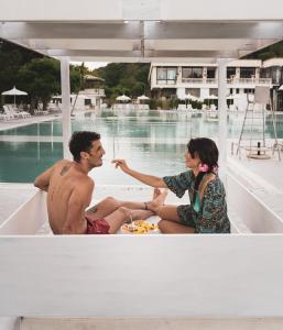 a man and woman sitting on a boat next to a pool at Hotel Terme Rosapepe in Contursi