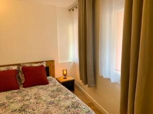 sypialnia z łóżkiem z czerwoną poduszką i oknem w obiekcie Studio cosy en plein centre historique de Rennes w mieście Rennes