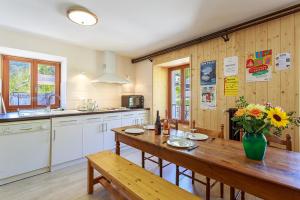 une cuisine avec une table en bois et un vase de fleurs dans l'établissement GITE AUBERGE L'HERBE TENDRE, à Saint-Pierre-dʼEntremont