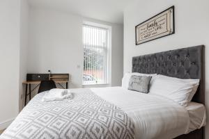 a white bedroom with a large bed with a gray headboard at York Villas Free Parking Included in Liverpool