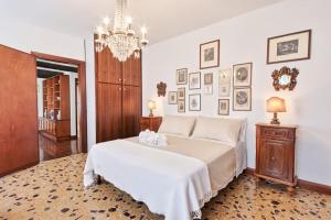 una camera da letto con un grande letto bianco e un lampadario a braccio di San Marco Bell Tower House a Venezia