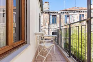 una sedia bianca seduta su un balcone con finestra di San Marco Bell Tower House a Venezia