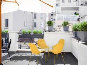 a patio with yellow chairs and a table on a balcony at numa I Vici Rooms & Apartments in Rome