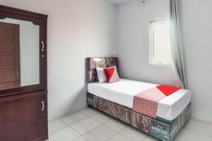 um pequeno quarto com uma cama e um espelho em SPOT ON 92000 3m Kost Dan Homestay em Manado