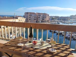 een tafel met een fles wijn op een balkon bij Béréa - Les Cormorans - Vue port et mer in Frontignan