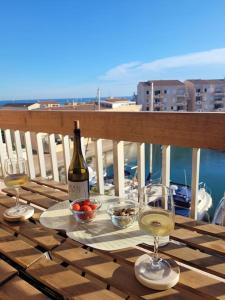 una bottiglia di vino e due bicchieri su un tavolo di Béréa - Les Cormorans - Vue port et mer a Frontignan