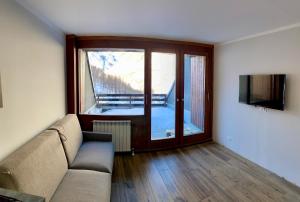 a living room with a couch and a large window at Cervinia Ski In Ski Out - Family Studio in Breuil-Cervinia