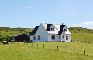 uma casa branca numa colina com uma vaca num campo em Strath Glebe em Kilbride