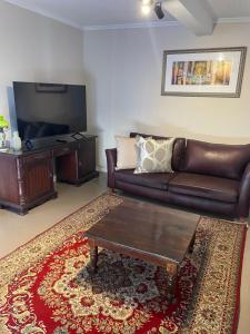Mount Road Suites في بورت اليزابيث: غرفة معيشة مع أريكة جلدية وتلفزيون