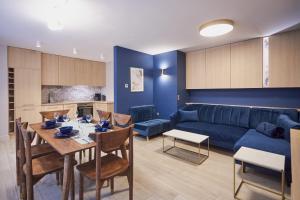 a living room with a table and a blue couch at Timber Apartments by Baltic Home in Świnoujście