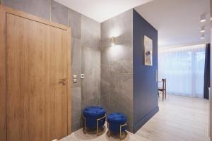 a bathroom with a shower and two blue stools at Timber Apartments by Baltic Home in Świnoujście