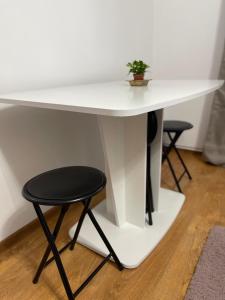 a white table and stool with a plant on it at BUTTERFLY FAMILY APARTMENT SIBIU in Sibiu +13 photos
