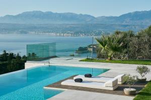 a swimming pool with a white couch sitting next to the water at Villa Niolos II in Stérnai