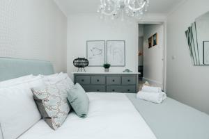 a bedroom with a white bed with pillows and a chandelier at Central Hidden Gem in Henley on Thames