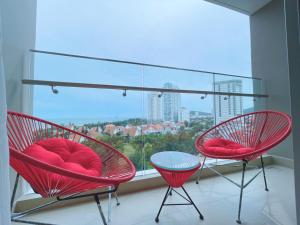 two red chairs in front of a large window at Luxury The Song Vung Tau Apartment Homestay in Vung Tau