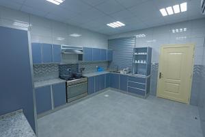 a large kitchen with blue cabinets and a yellow door at Al Wadi House , بيت الوادي in Ras al Khaimah