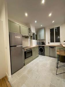 una cocina con nevera de acero inoxidable y armarios en Paris15 eme Chic appartement atypique et calme, en París