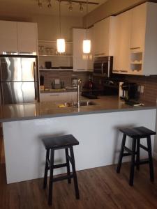 a kitchen with two stools and a counter with a sink at Mike's Studio off Whyte! in Edmonton