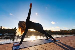 a woman doing a yoga pose next to a body of water at The Lakeside Hotel & Leisure Centre in Killaloe
