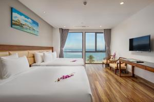 Cette chambre comprend deux lits et un bureau. dans l'établissement Alisia Beach Hotel Da Nang, à Đà Nẵng