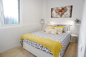 een witte slaapkamer met een bed met een gele deken bij La Garita beach in La Garita